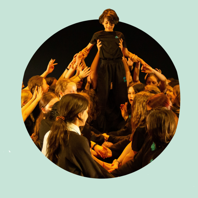 Group of children dressed in black lifting one person above them during a performance or activity